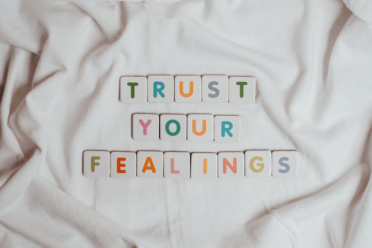 Colorful tiles spell out 'Trust your feelings' on a fabric background.